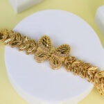 Gold bracelet featuring a butterfly centerpiece and leaf motifs on either side.