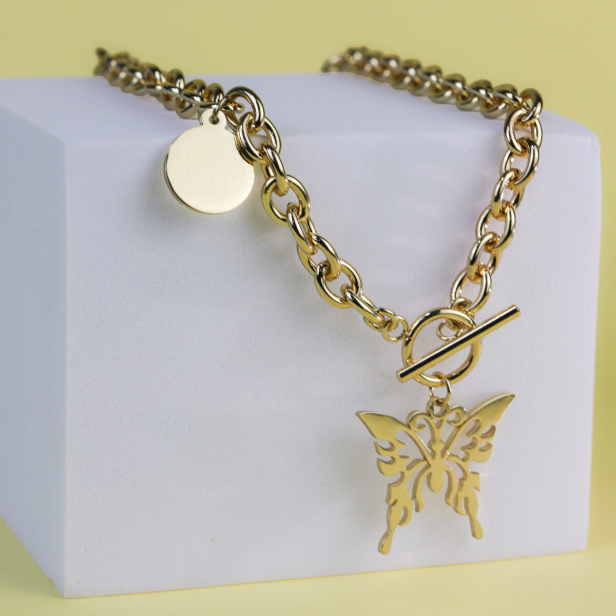 Gold chain necklace featuring a butterfly pendant and a toggle clasp on a white display.