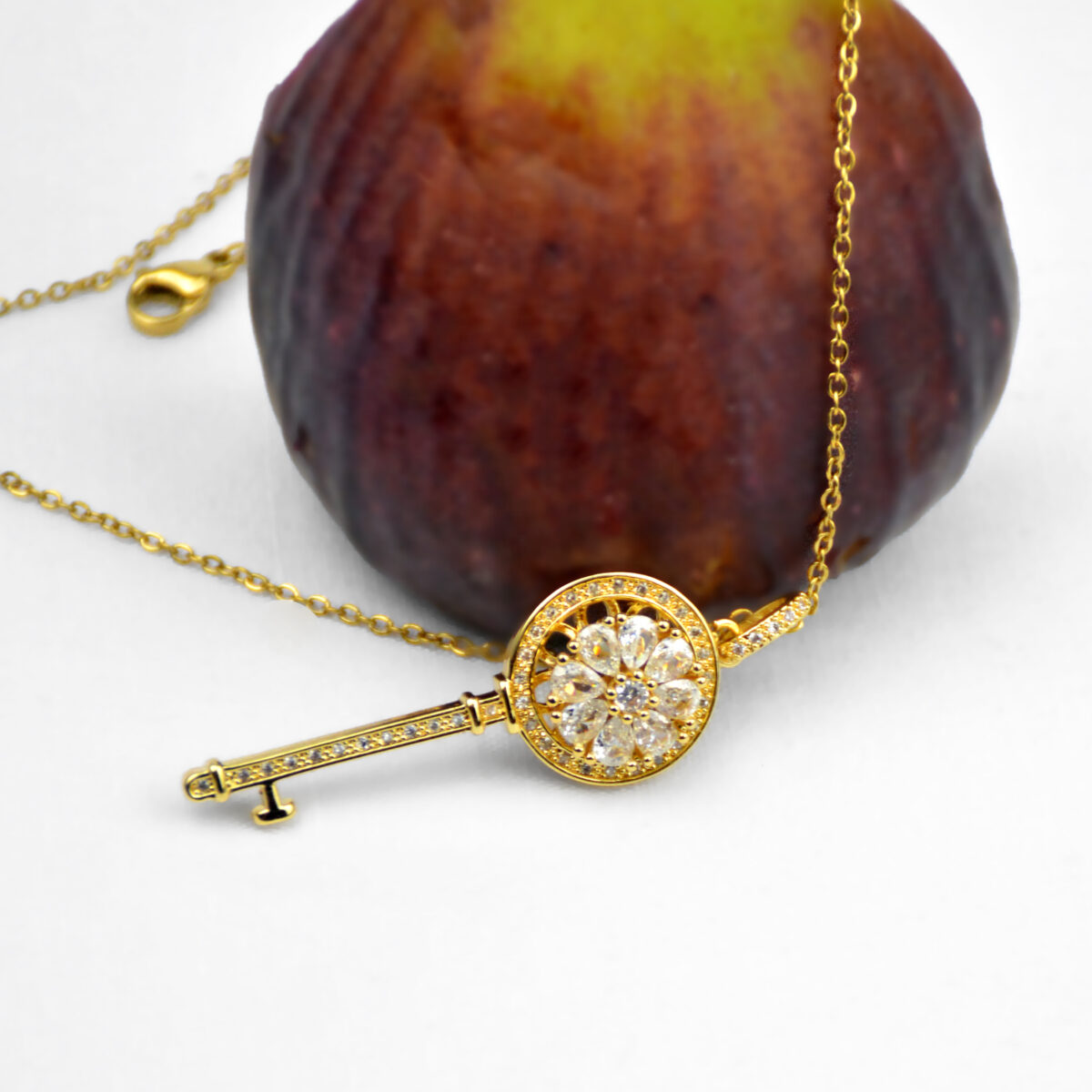 Gold key pendant necklace adorned with diamonds, featuring a floral design and a delicate chain, perfect for elegant jewelry collections.
